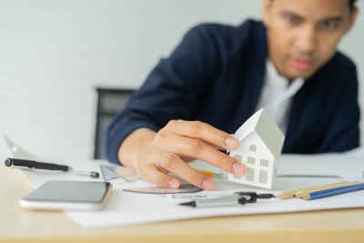 近距离的建筑师手握家模型在办公桌旁测量和设计有关房地产住宅和建筑项目的工作理念