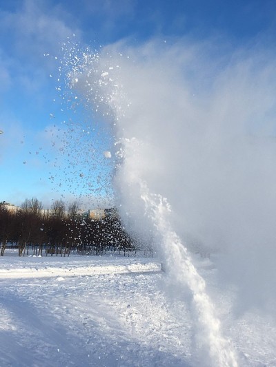 在晴朗的冬日里，吹雪机下的雪波映衬着湛蓝的天空
