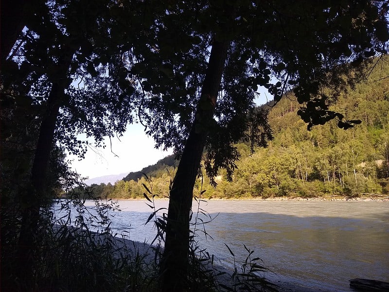 日落时分的河岸，有小山和森林