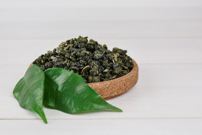 白木桌软木碗里的干绿茶叶