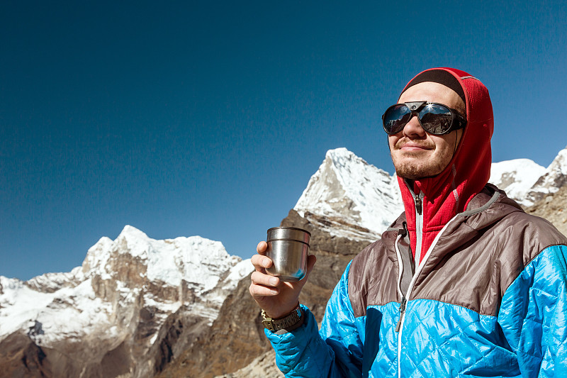 年轻的登山运动员在热杯中休息