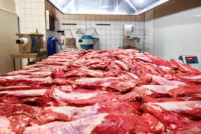 屠宰场的桌子上放着新鲜的生牛肉，背景是肉馅设备