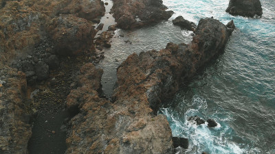 冰冻熔岩的鸟瞰图，在海岸上。一个火山起源的海滩，岩石在水旁边的天然水池，西班牙特内里费，一个秘密的地