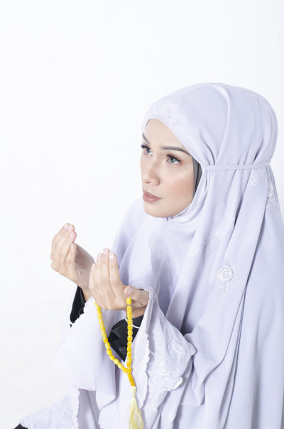 年轻女子祈祷时戴着披肩，手里拿着念珠
