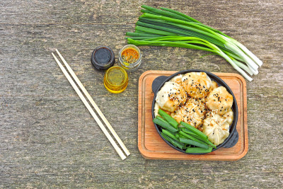 在铸铁煎锅里放上酱油和葱的饺子。