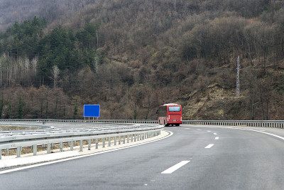 红色现代舒适的旅游车在高速公路上行驶。