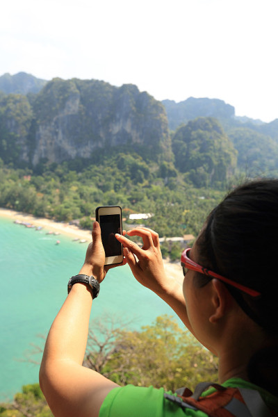 徒步旅行者在海边用智能手机拍照
