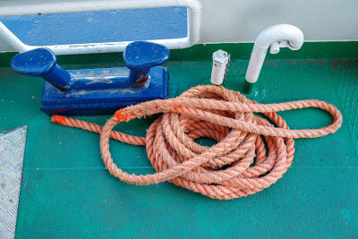 Worn mooring bollard with heavy ropes on the deck 