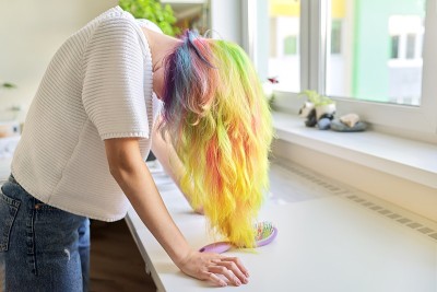 时尚少女用时髦的彩虹染发在家梳头发