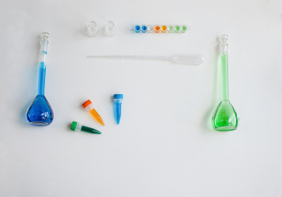 一套学校用品，生物或化学课上的光背景:玻璃烧瓶，镊子，吸管，塑料管铜和钴盐。理念:回到学校。Flat