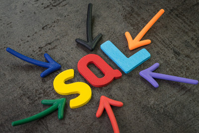 SQL是一种现代编程语言，用于数据库软件开发或应用的概念，多色箭头指向SQL字中心的黑色水泥黑板墙