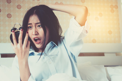 亚洲女孩看闹钟醒来晚了。