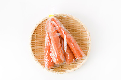 新鲜胡萝卜装于塑料袋，竹制滤锅，白色背景