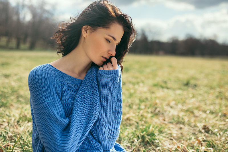 肖像的梦幻女性闭上眼睛与手在脸上。有魅力的黑发白种年轻女子与风的头发在室外，在春天或夏天，在公园。生