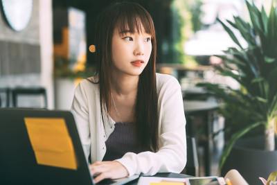 年轻的成年亚洲女大学生每天在咖啡馆使用笔记本电脑进行在线学习。