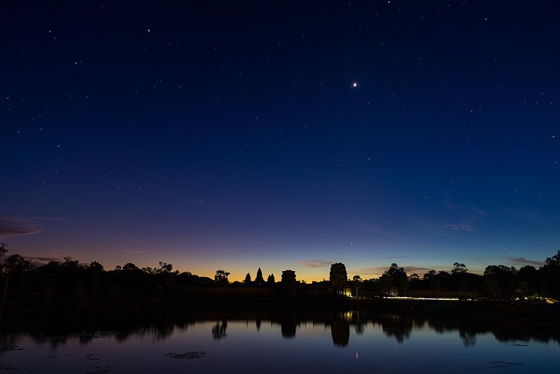 吴哥窟夜晚星空，黄昏主立面倒影在水塘上的剪影。柬埔寨的世界著名寺庙。