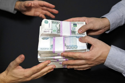 百万卢布在男人手里。在暗室里用俄罗斯卢布行贿。一个人给钱，另一个人拿走。贪污贿赂的概念。一笔不错的金