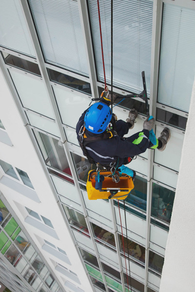 工业登山工人在清洗外立面玻璃时悬挂在住宅外立面建筑上