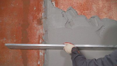 施工现场抹灰，找平墙面，检查质量。建筑地盘的产业工人。工人用灰浆抹平墙壁