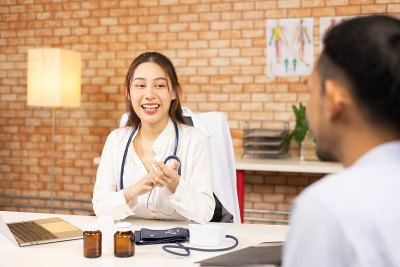 医生的手持视图测量他的病人的压力。一名医护人员正在为一名年轻女子检查血压。