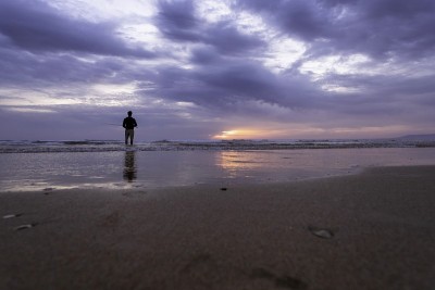 在葡萄牙里斯本的Costa da Caparica，一个年轻人在大西洋沿岸的公海上钓鱼。