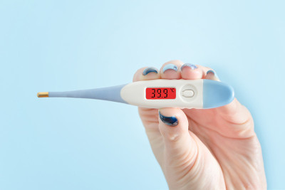 女性手握电子温度计。体温升高。近距离