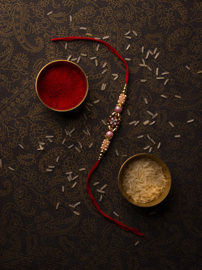 Raksha Bandhan背景与优雅的Rakhi和米粒深色纹理背景。
