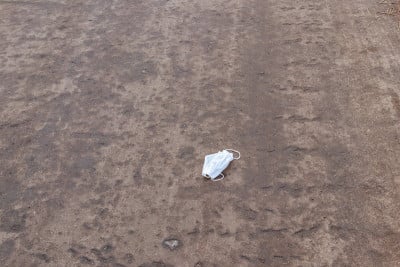 肮脏的用过的一次性医用口罩作为垃圾倾倒在柏油路上。在COVID-19浪费。冠状病毒大流行造成的污染