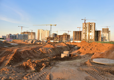 落日背景下的大型建筑工地，塔吊和建筑物