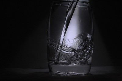 水进入透明/白色的玻璃与黑色背景与一些光