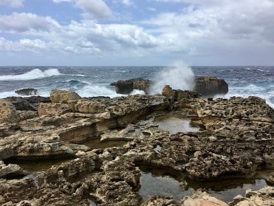 岩石海岸与多云的天空和海浪在海上