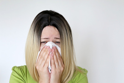 生病的女人用手帕擤鼻子