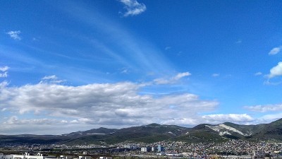 一个山城的全景。一望无际的绿意，海边的山脉，点缀着一座座房屋，在阳光明媚的春日。
