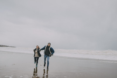 一对年轻夫妇在冬天的海滩上散步