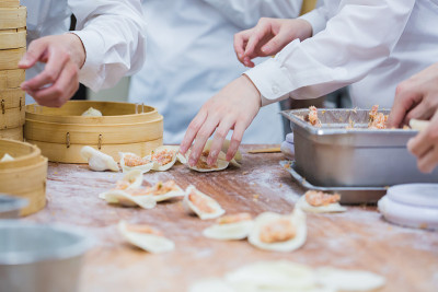 在一家餐馆里，厨师们正在传统的竹制蒸笼里煮中国饺子。
