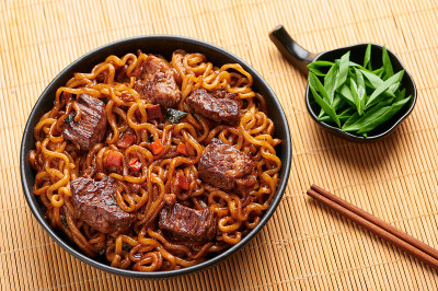 黑碗里的牛肉拉面。Jjapaguri是一道很受欢迎的韩国菜，里面有拉面、乌冬面和牛排。