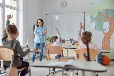 在现代轻装教室里，快乐的小学生们正在举手上课