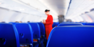 网页横幅乘客座位在飞机，飞机内部和空姐的背景。空中小姐为旅客提供服务。服务理念，旅游理念。