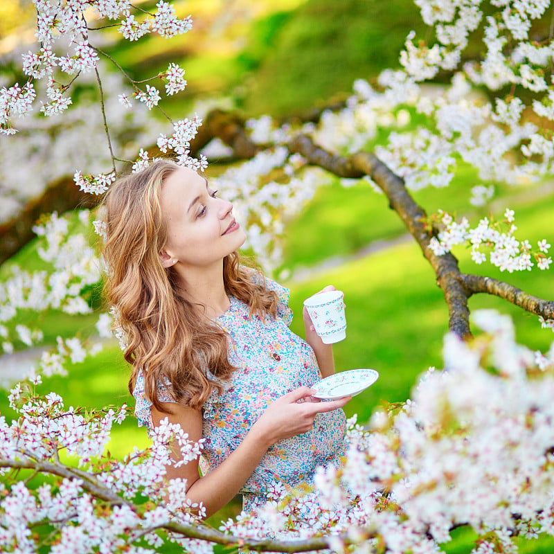 在樱花园里喝着茶的女人