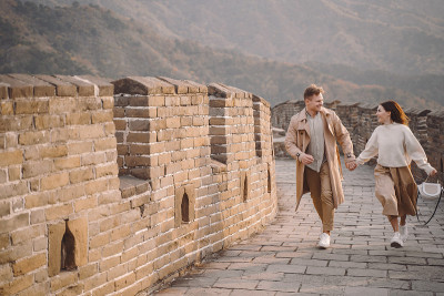 一对年轻夫妇在中国长城上跑步和旋转