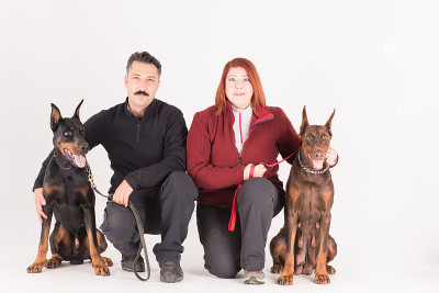 年轻夫妇与训练有素的杜宾保护犬摆姿势