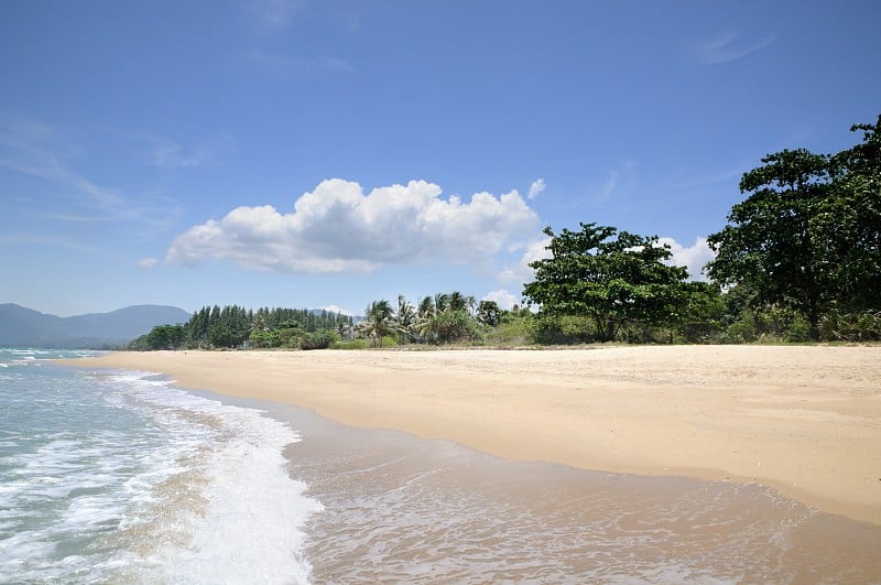 碧绿的热带海浪，海浪的泡沫，空荡荡的沙滩上的蓝天。