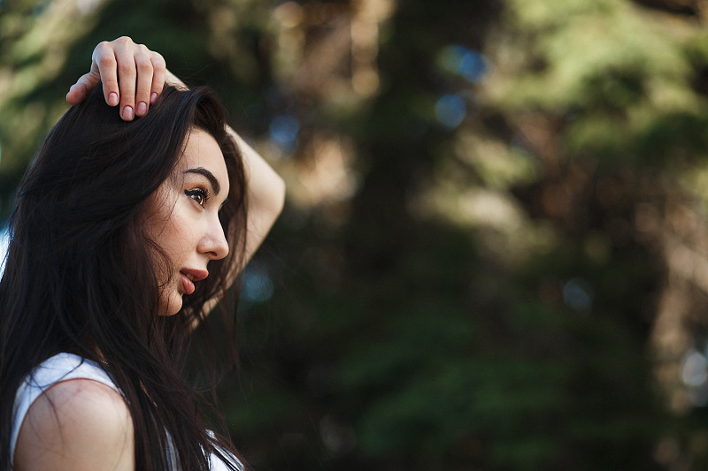 特写白人妇女侧脸肖像户外。褐色的头发，多汁的嘴唇和棕色的眼睛。