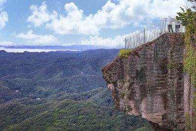 一对夫妇从后面站在野木山地狱山的悬崖上。