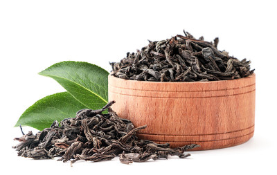 红茶装在木盘子里，绿叶在白色的背景上。孤立的