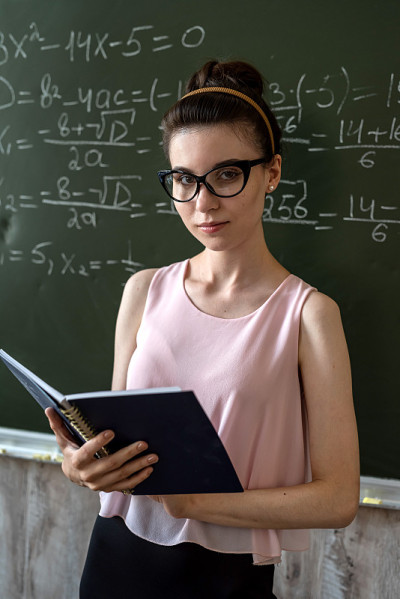 认真的女老师在大学黑板旁讲解数学公式