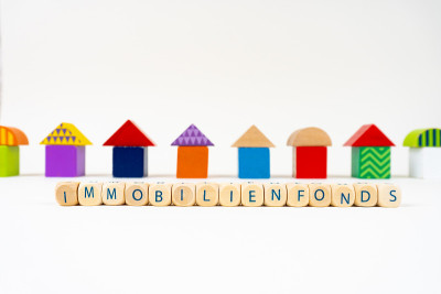 五颜六色的玩具房子前面的木块上写着“Immobilienfonds”(德国的房地产基金)