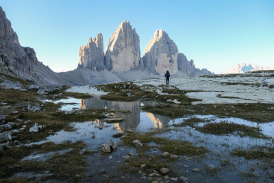 一名男子徒步旅行，欣赏意大利Dolomites地区的Drei Zinnen山。群山倒映在小桨里。荒凉