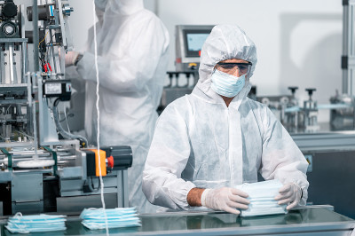 科学家们穿着统一的防护服。检查口罩的生产过程。在工厂的实验室里。新冠肺炎的安全防护理念。