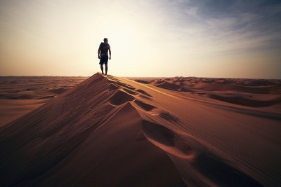 夕阳下，人在沙丘上行走